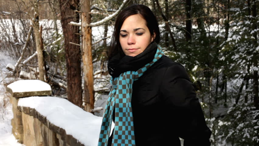 Female standing against brick wall in nature with scarf on.