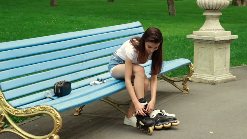 young cute girl ties the laces on roller skates