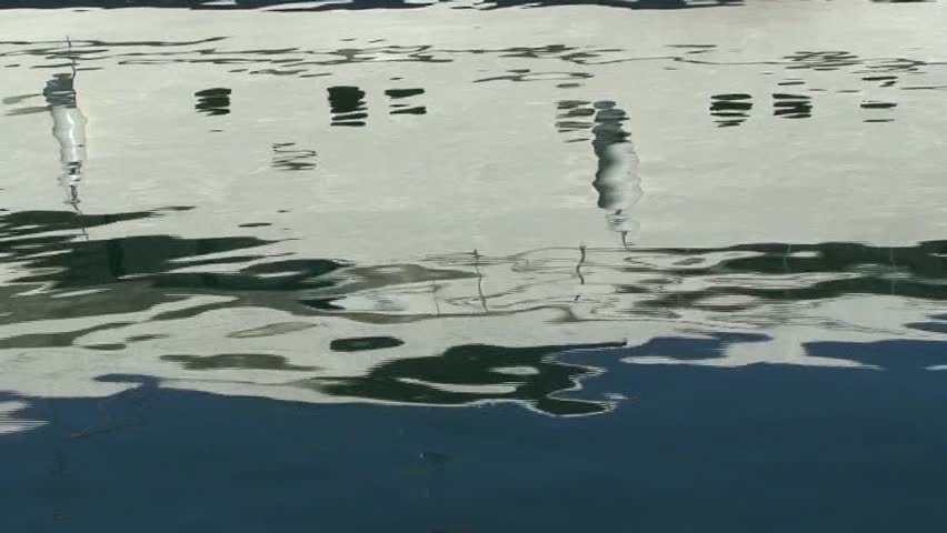 Ripples on water with reflection of yacht in port and bird sounds