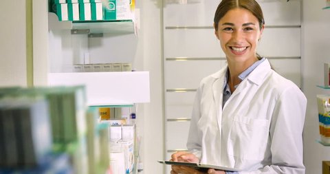 Portrait of a beautiful young girl (woman) pharmacist, consultant, working at a pharmacy, selling and checking medication, smiling, giving advice. Concept: profession, medecine, medical education.