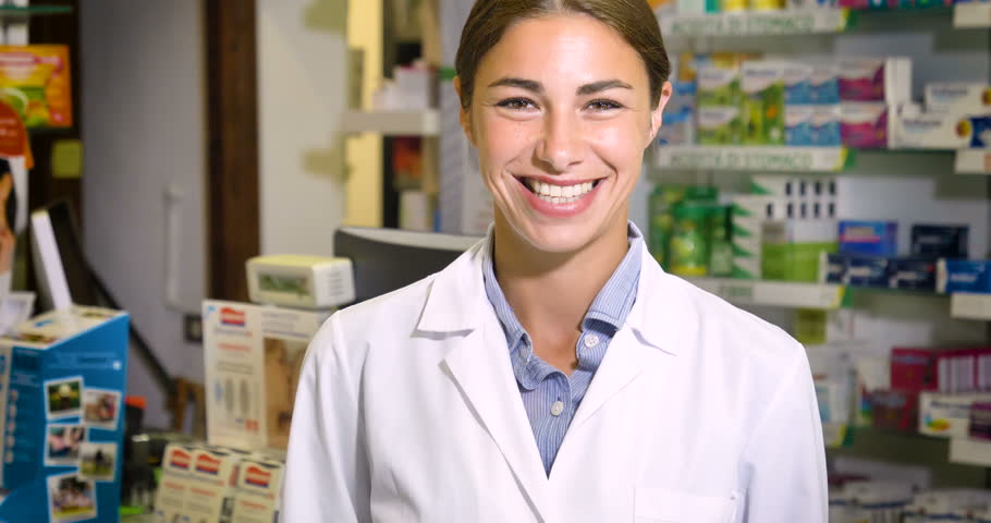 Portrait of a beautiful young girl (woman) pharmacist, consultant, working at a pharmacy, selling and checking medication, smiling, giving advice. Concept: profession, medecine, medical education.