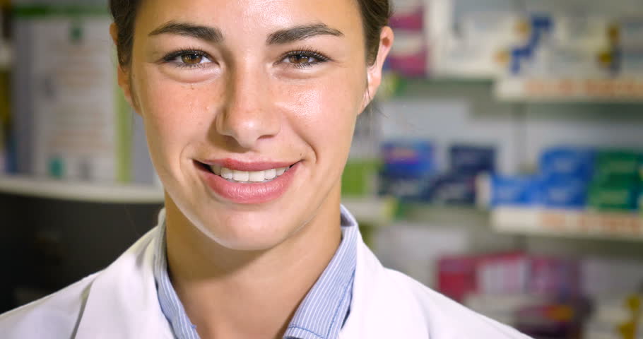 Portrait of a beautiful young girl (woman) pharmacist, consultant, working at a pharmacy, selling and checking medication, smiling, giving advice. Concept: profession, medecine, medical education.