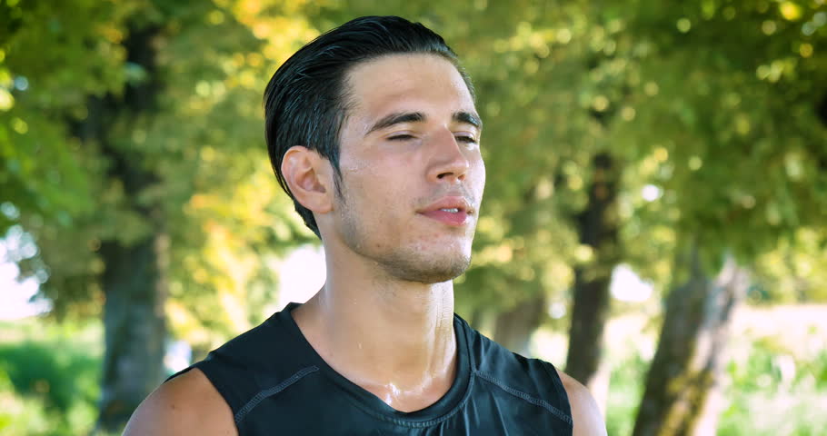 Portrait of a handsome young guy sportsman, drinking water, wet, smiling, wearing sports clothes, running on the street. Concept: to love sports, a healthy lifestyle, to be beautiful, muscles, happy.