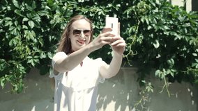 Pretty girl recording herself on smartphone while standing outdoors, steadycam shot