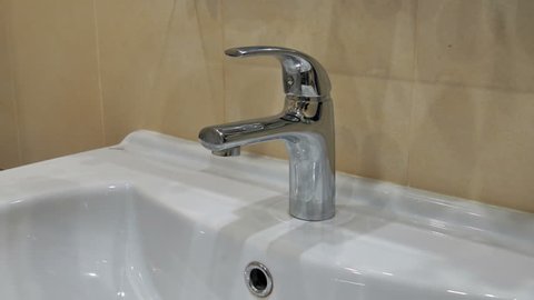 Man opens the tap with water close up
