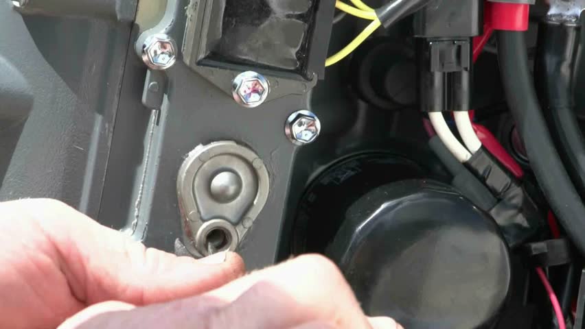 Mechanic removes a sacrificial anode from outboard motor, checks for corrosion