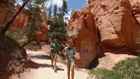 Hikers hiking in Bryce Canyon. Couple walking smiling happy together. Multiracial couple, young Asian woman and Caucasian man in Bryce Canyon National Park landscape, Utah, United States.