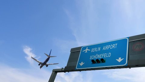 airplane flying above berlin airport signboard