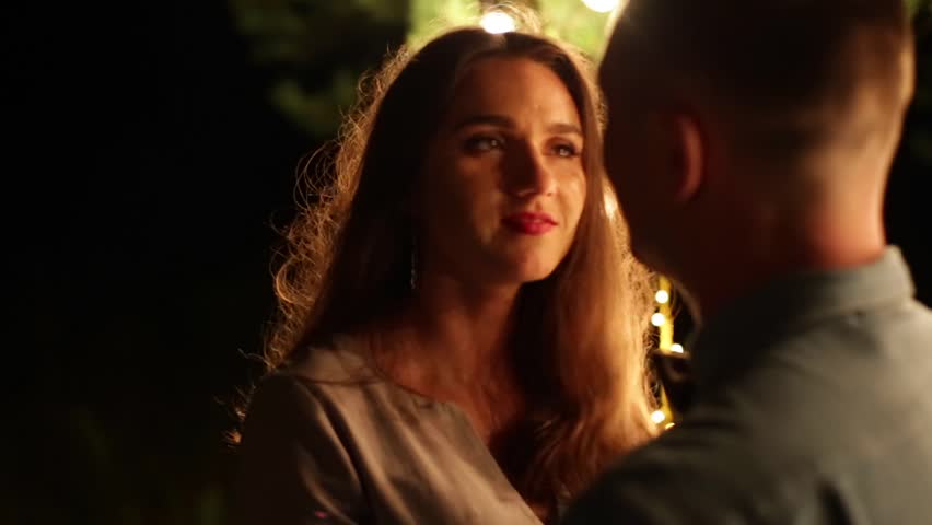 A young married couple talking and laughing in the evening surrounded with lights and candles.