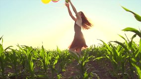 Beauty girl running on summer field with colorful air balloons over clear sunset sky. Happy young healthy woman enjoying life, nature outdoors. Running, Spinning female. 4K video slow motion 240fps