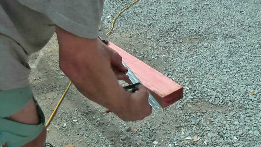 Carpenter uses builders square to mark his saw cut line with a pencil on framing