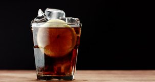 glass with ice cubes and lemon slide and cola. rom cola, fresh drink, ice cubes and bubbles texture