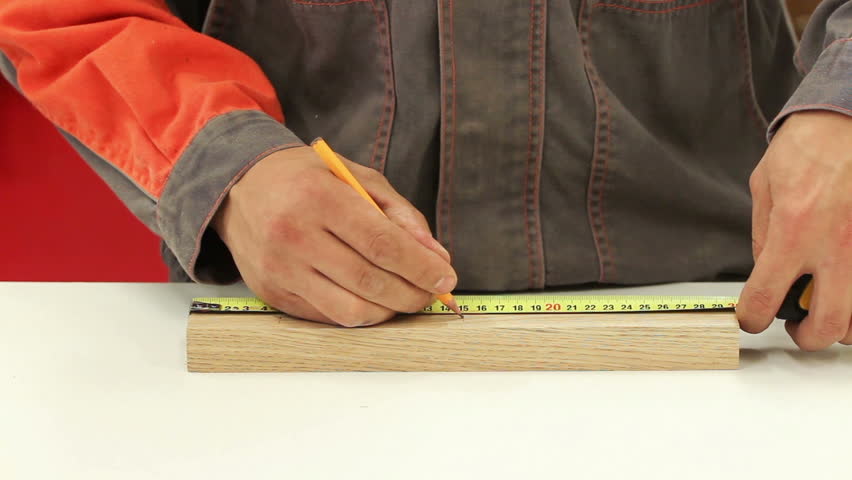 Carpenter working with tape measure,marking wooden desk (selective focus)