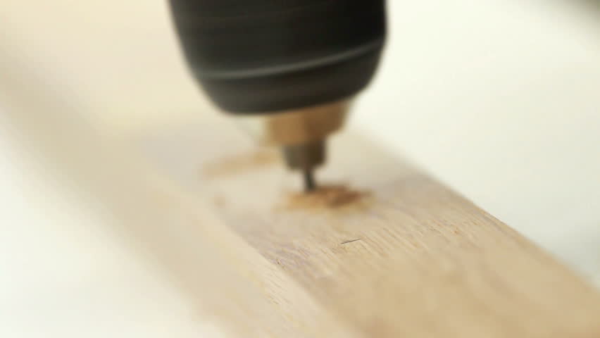 Carpenter working with electric machine, drilling into wooden desk (selective
