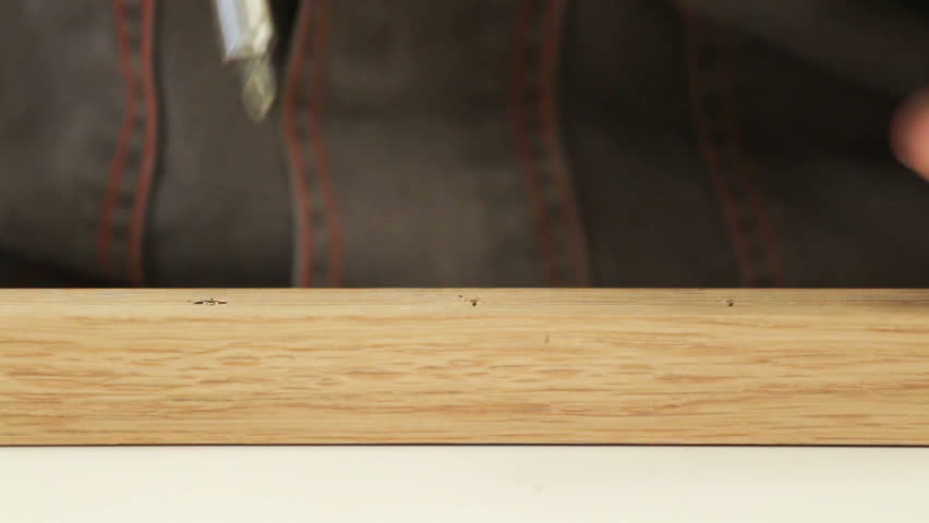 Carpenter driving screw into wooden desk (selective focus)