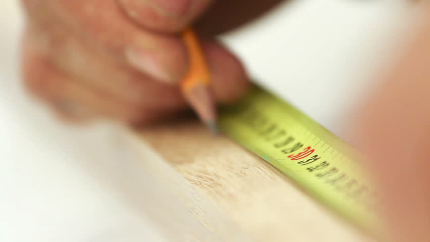 Carpenter working with tape measure,marking wooden desk (selective focus)