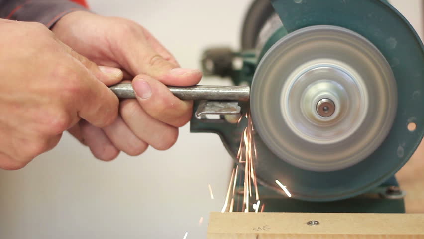 Carpenter working with electric machine, grinding metal drill (selective focus)