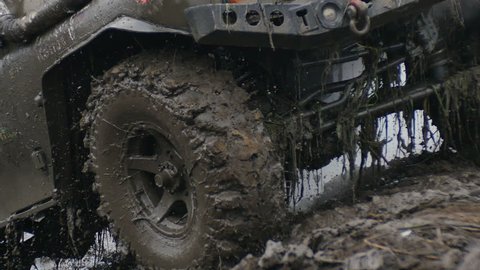close up of wheel in the Mud. Off-road car wheel slips in the mud, but moves slowly.