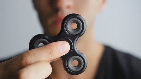 Man playing with fidget spinner. Close up spinner or fidgeting hand toy rotating on man's hand