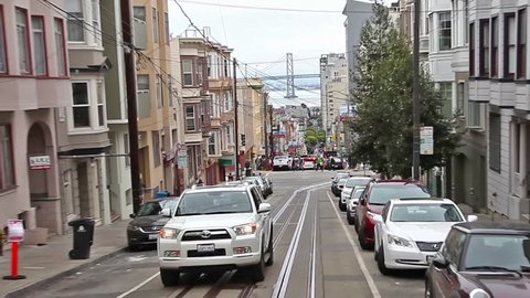 San Francisco, California, United States - August 17, 2016: Cable Car, Powell-Manson line , turning in Washington street, at cable car corner, looking the Oakland Bay Bridge on the horizon.