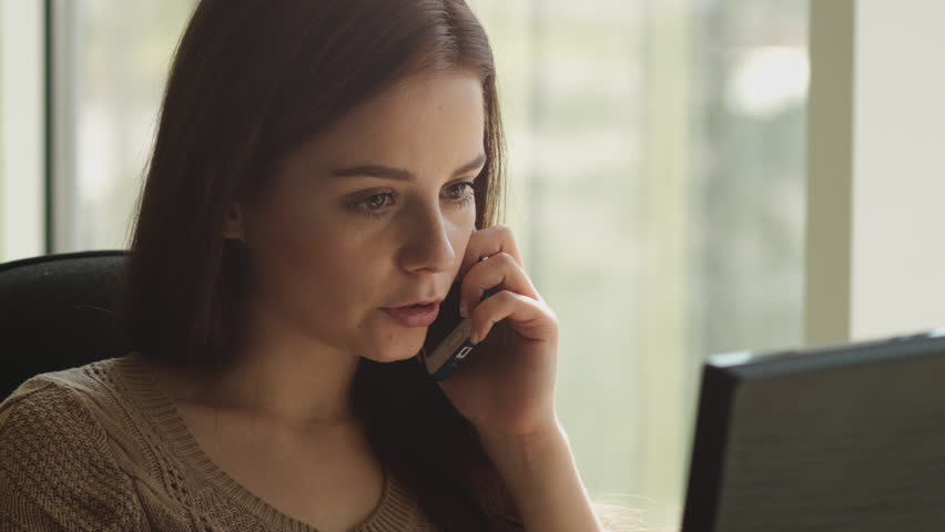 Young attractive businesswoman talking on the phone in the office sitting at a table by the window. ProRes | Shutterstock HD Video #28607485