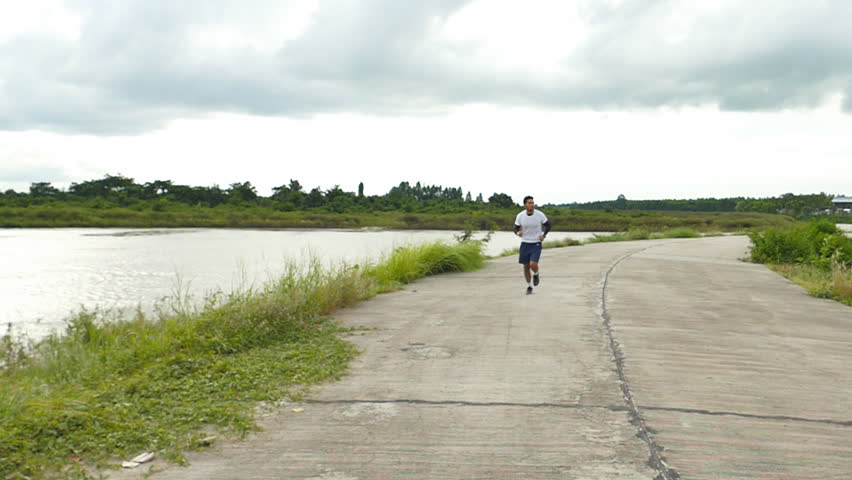 Man jogging on the river side while rain coming, slow motion shot at 120fps.