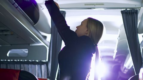 Airplane Stewardess/Flight Attendant Closes Baggage Compartments. Plane is Ready to Take off. Shot on RED EPIC-W 8K Helium Cinema Camera.