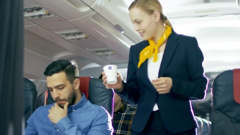 Airplane Stewardess/ Flight Attendant Brings Coffee for Handsome Hispanic Male Gentleman. They're Inflight. Business Class of a Commercial Aviation Interior is Visible.