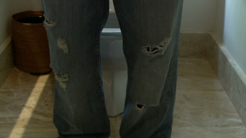 Male pulling jeans down and sitting on the toilet tapping his foot