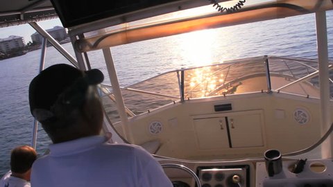 Deep Sea Fishing Captain drives boat at sunset sunrise