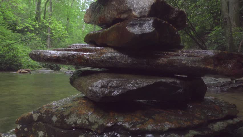 Girls building rock pagoda in creek by Looking Glass Falls in North Carolina