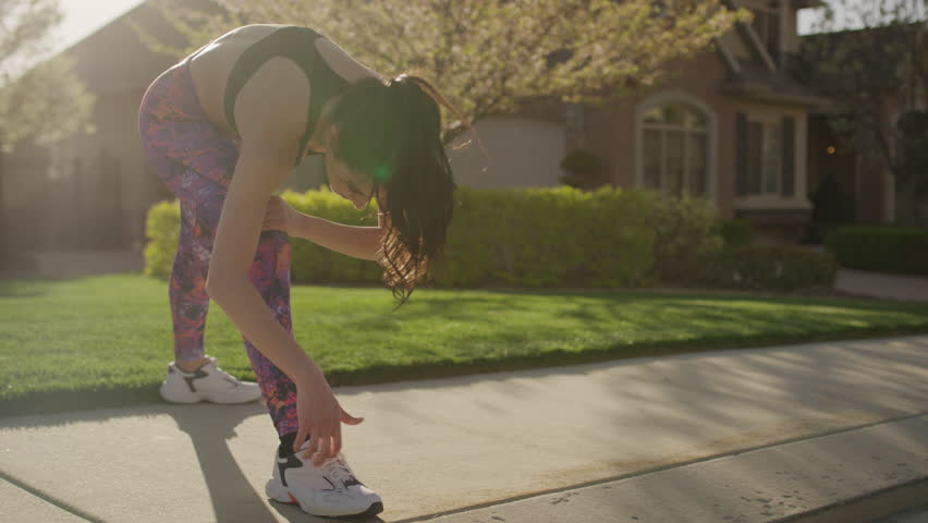Medium slow motion panning shot of woman stretching legs on sidewalk / Cedar Hills, Utah, United States | Shutterstock HD Video #28628659