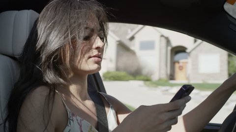 Close up of woman driving distracted with cell phone / Cedar Hills, Utah, United States