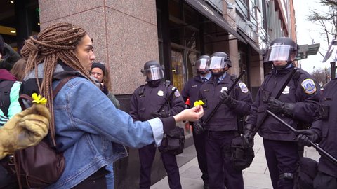 Washington D.C.-2010s: A woman offers a flower to police in riot gear at the inauguration of Donald Trump in Washington DC.
