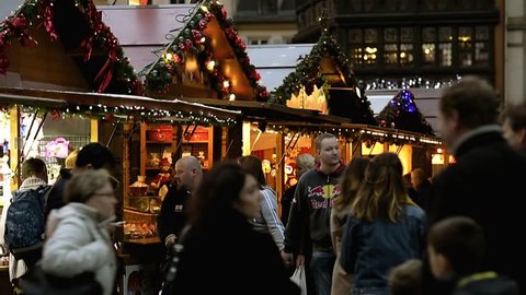 STRASBOURG, FRANCE - CIRCA 2017: Tourist couple spotted in crowd admiring the Christmas market stall with toys people and Christmas decorations food in central Strasbourg, Alsace, France market