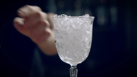 Bartender making red icy cocktail. He pouring red liquor into a glass
