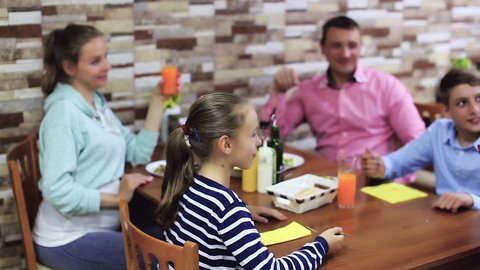 Waitress bringing delicious dessert to young visitors of family cafe