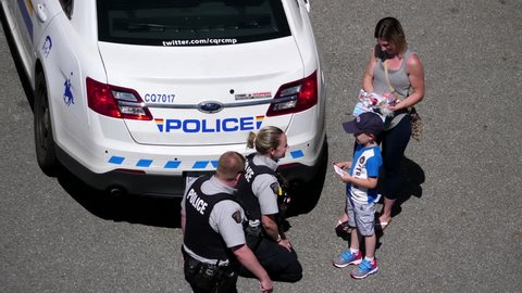 Coquitlam, BC, Canada - June 26, 2017 : Top shot of police officer hugging with children beside police car with 4k resolution