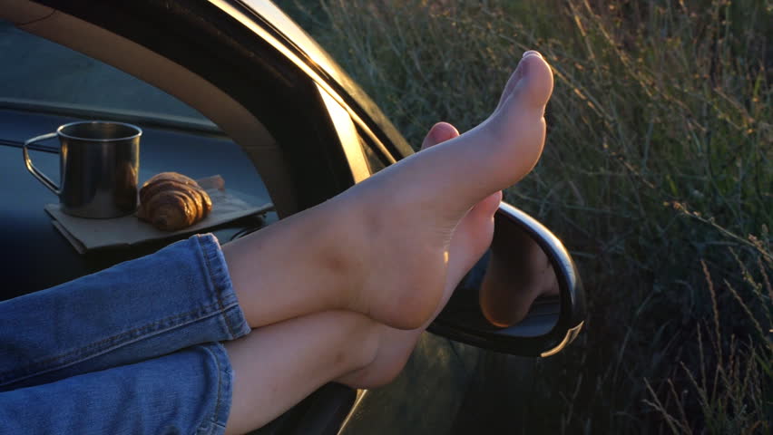 Woman legs out the windows in car . Conceptual freedom, travel and holidays image with copy space.
