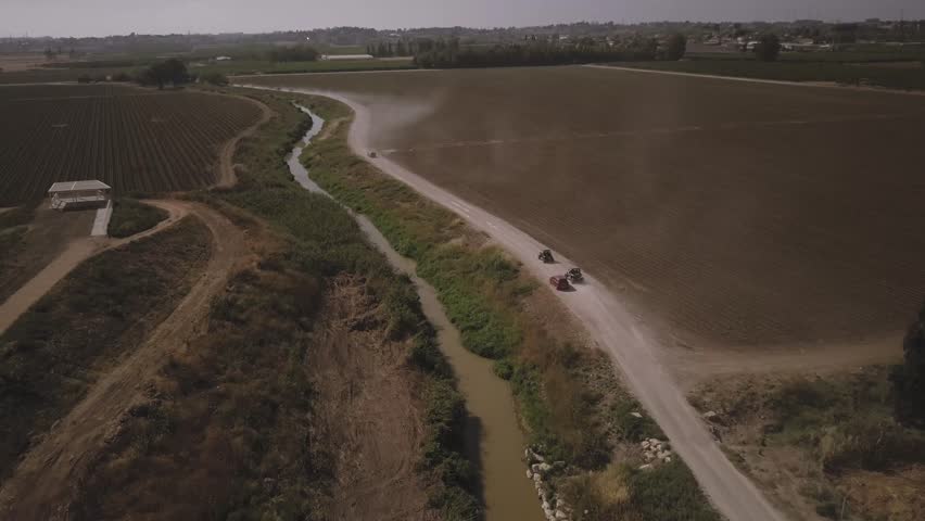 4K - Aerial view of country side terrain, ATVs going away by on a dirt path | 2017