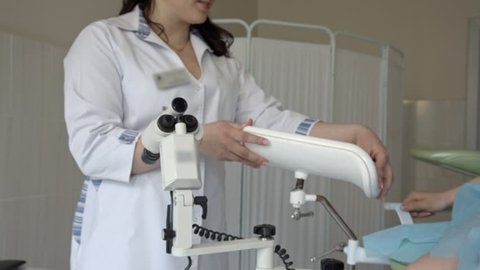Female gynecologist cheerfully talking to patient lying in gynecological chair.