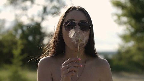 The girl blows away the dandelion