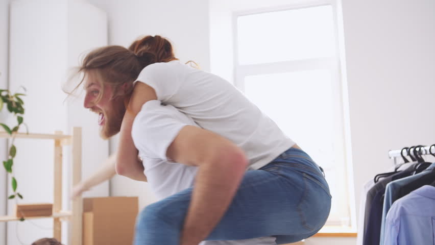 Cool young Caucasian pair having fun in their new apartment and rejoicing in slowmotion. Concpet of happines and joy Royalty-Free Stock Footage #28672111