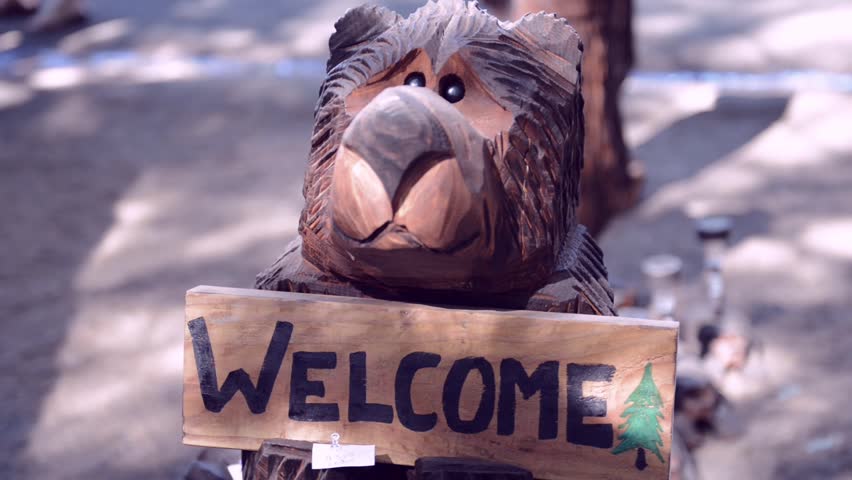 wooden bear holding a welcome sign