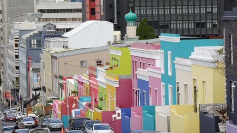 CAPE TOWN, SOUTH AFRICA CIRCA JULY 2017, view of Bo Kaap Wale street pastel colored houses perspective with top of mosque tower and city buildings behind with cars & people in street