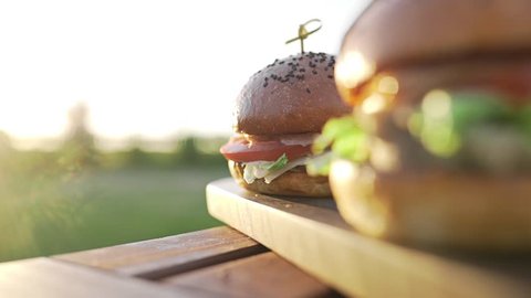 Hot burgers on the wooden board in the sunset sunlight at the coutrisude, fast food meals, cooking food, cooking on the open fire, grill and barbecue