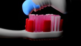 Tooth paste and brush. Applying blue toothpaste on red toothbrush against black background in slow-motion. (av37893c) - Powered by Shutterstock - Get 15% off with code: PIKWIZARD15