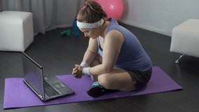 Chubby girl nervously reading workout and diet plan from her trainer on laptop