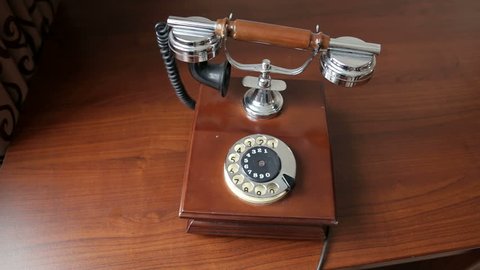 Old brown retro phone stands on a wooden table, close-up. Vintage brown phone on old wooden table background.