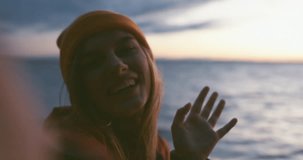 Happy Caucasian girl making selfie or a video call on a large lake, smiling and laughing into camera. Smartphone camera POV. 4K UHD